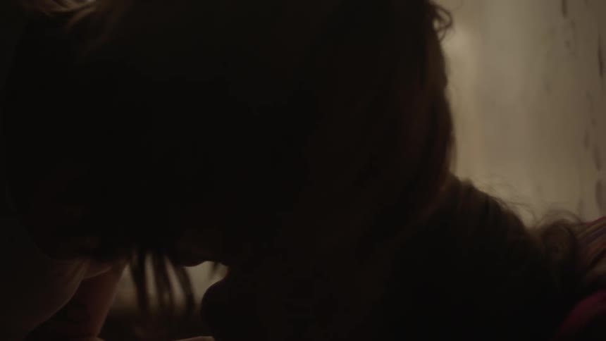 A man and a woman are kissing in bed