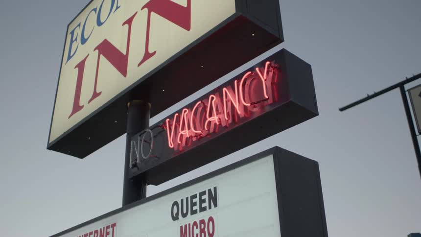 A hotel vacancy sign lights up in red