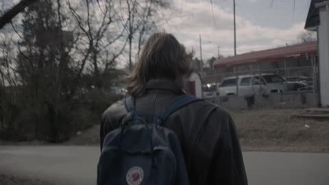 Person wearing a backpack walking down a country road