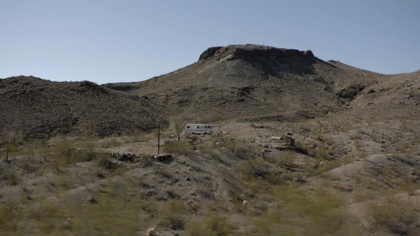 A recreational vehicle is on a hill near a mountain range
