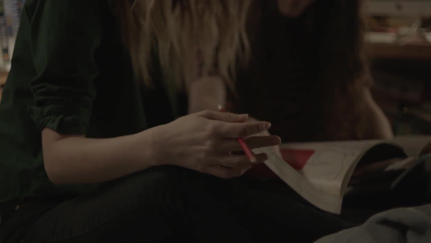 Two teenagers are sitting on interacting as they look at a book