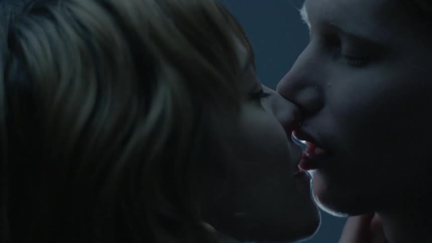 A man and woman kiss as lights flash in a dark room