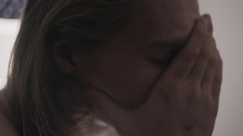 A woman is rubbing her face and is obviously worried