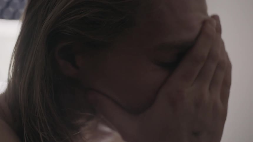 A woman is rubbing her face and is obviously worried