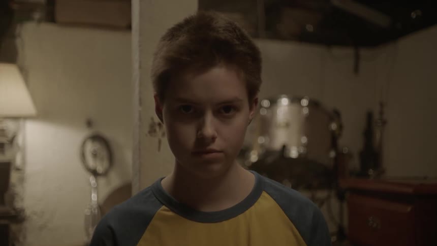 A boy is standing in front of some drums