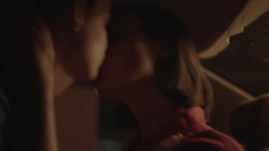 Two people kissing and caressing in a dimly lit room