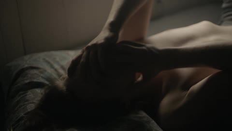 Man lays in bed with his hands over his face