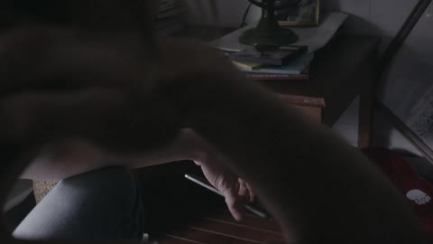A woman looking at her phone while sitting at a desk at home