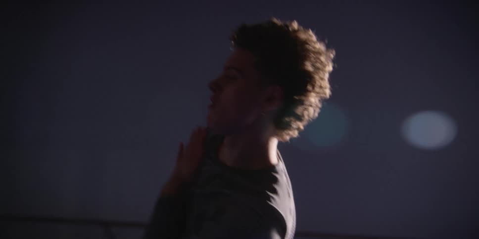 Male dancer dances in studio lit by spotlight
