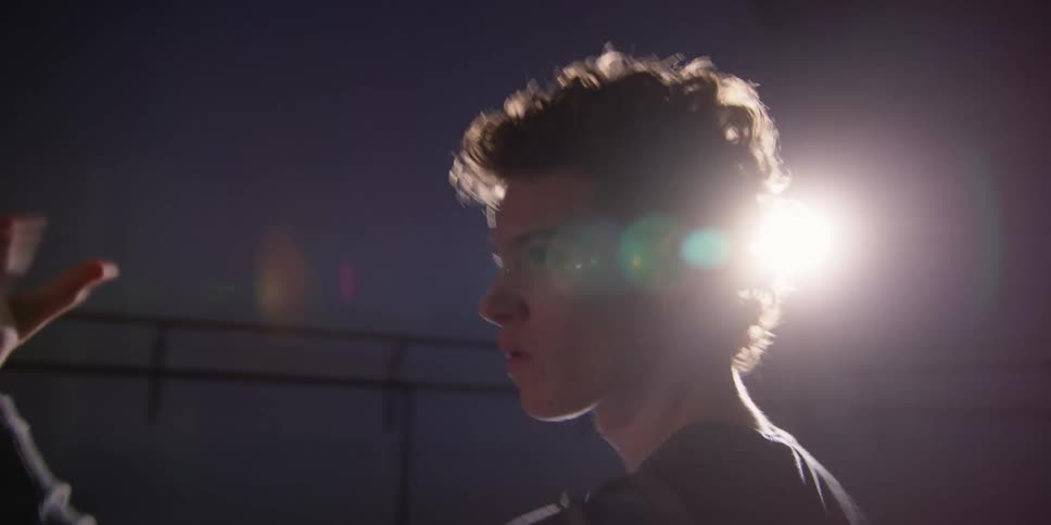 A dancing man moves with his hands in a dark room