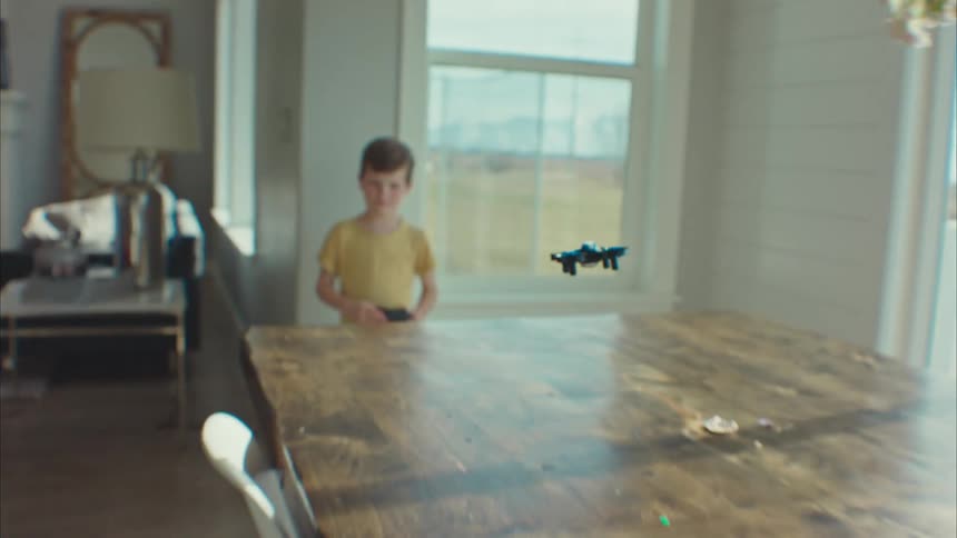 A boy is flying a small drone at home