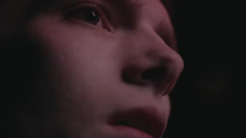 A person in a dark area with flashing colored lights on their face