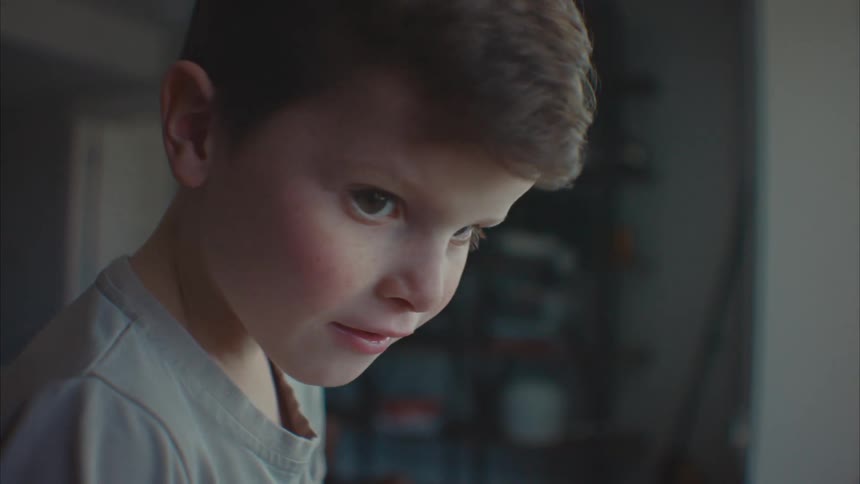 A child stands near a window and smiles