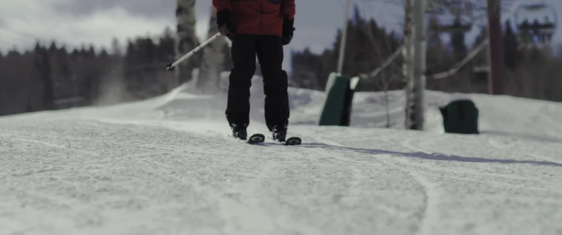 A skier slowly starting to go down a gentle slope