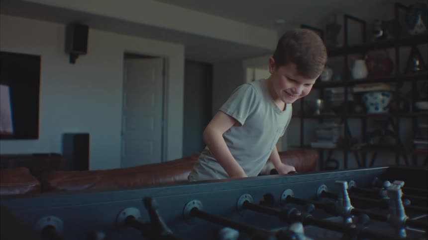 A child playing with a foosball table in a room