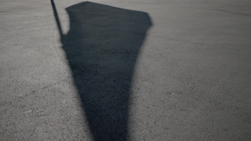 The shadow of a billowing flag is cast on the ground