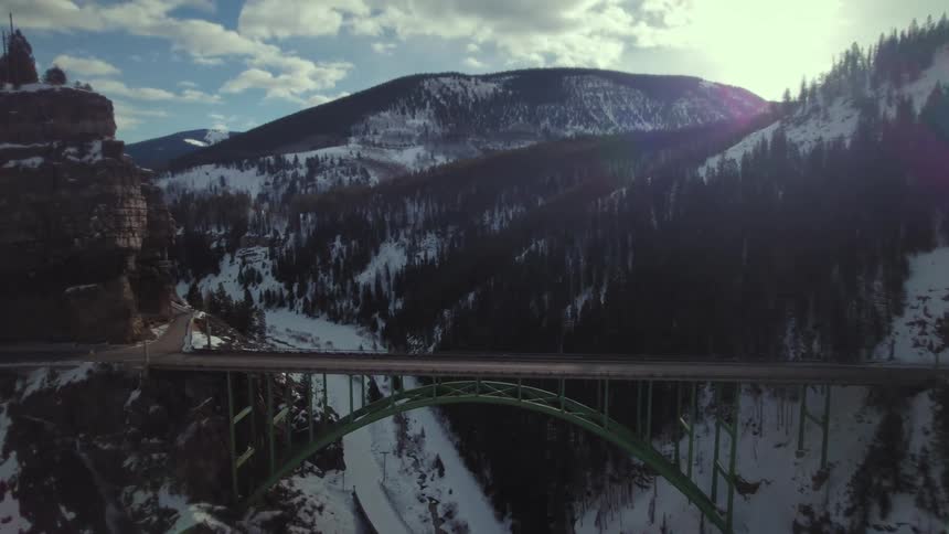 A car travels over the bridge crossing the mountains