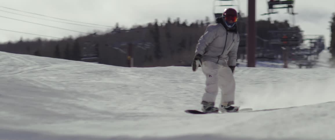 Person riding a snowboard through the park in the mountains covered by snow