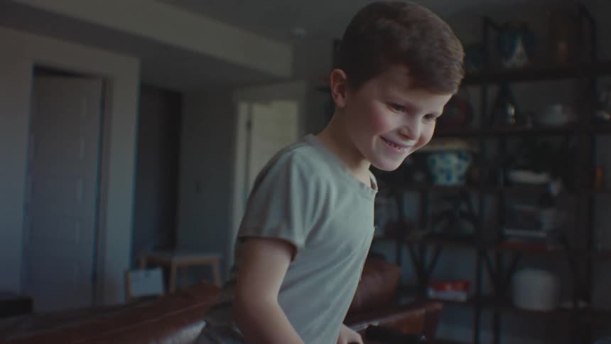 Boy smiles while playing with foosball table at home