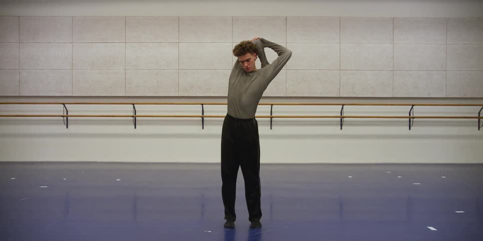A dancer in a bright room doing stretches before dancing
