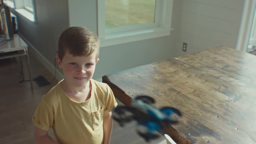A boy is flying his small drone in the house