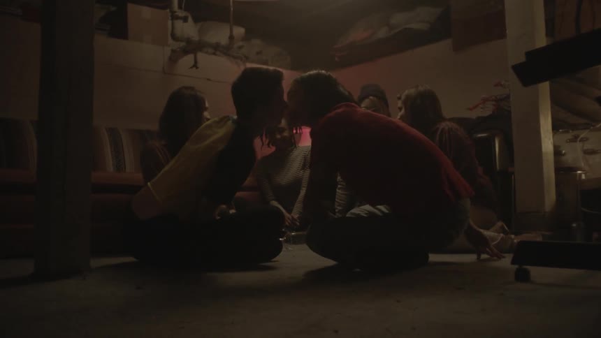 Group of people playing spin the bottle in a dimly lit room