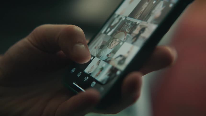 Fingers scrolling through photos of people on the cell phone screen