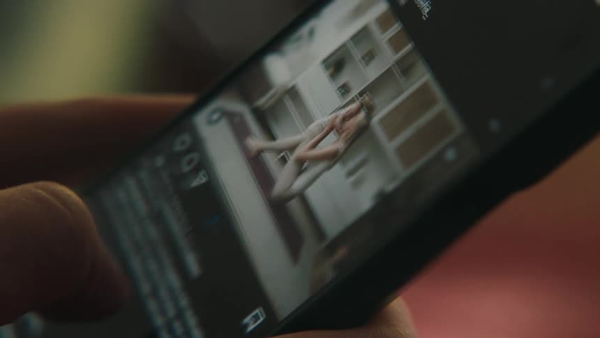 A hand scrolling social media on a smart phone to look at photos