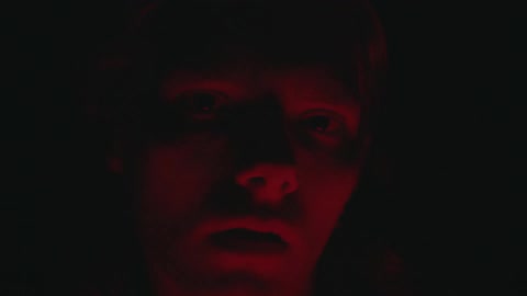 A man is in the dark with light flashing on his face