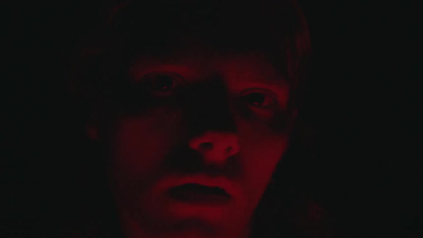 A man is in the dark with light flashing on his face