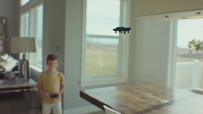 Little girl indoors in the living room playing with the remote control plane