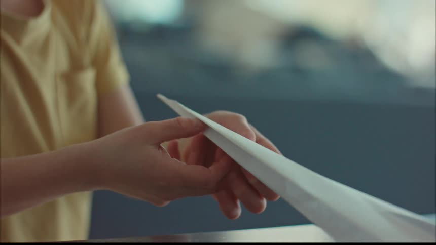 A young man finishing the folding of a paper plane
