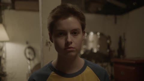 Teenager staring forward in a dimly lit room