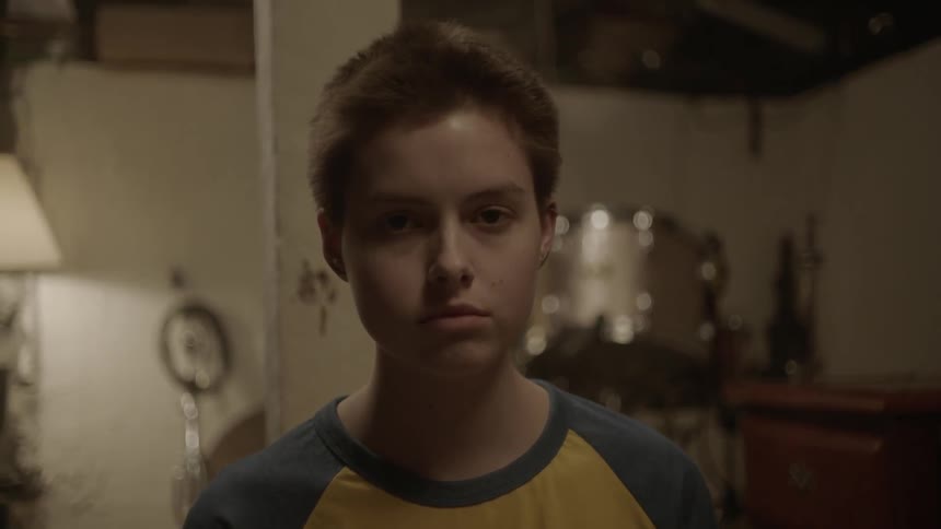Teenager staring forward in a dimly lit room