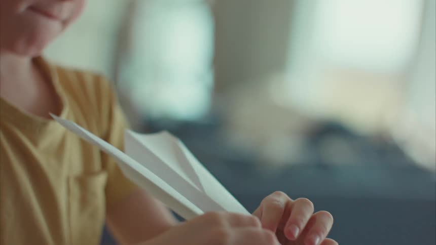 Portrait of a little boy making a paper airplane