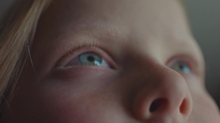 Closeup on the face of a little blonde girl with light eyes