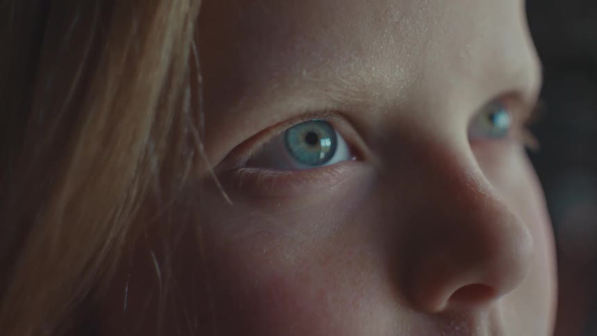 A young girl moves her eyes around and stares