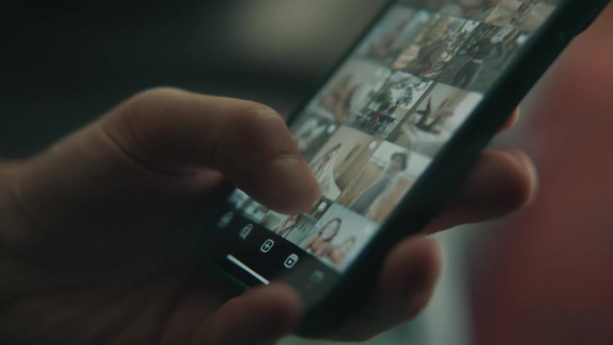 A hand scrolling through a photo gallery on a smart phone