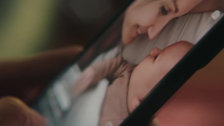 Person holds smartphone showing video of mother and baby
