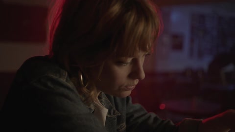 Solemn looking woman looking at her drink while sitting at a bar