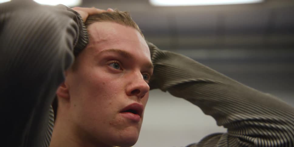 A young man rubs his hands over his face and hair