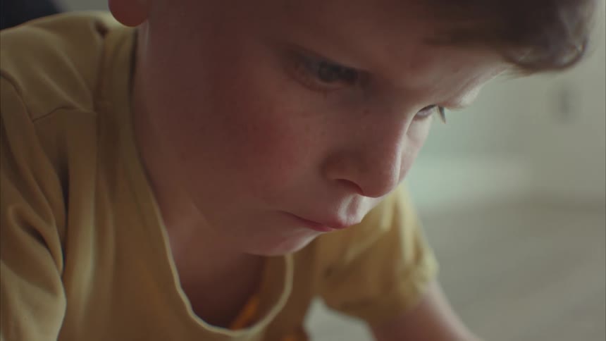 A young boy lying on the floor focused yet smiling