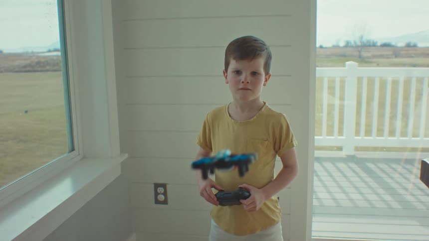 A little boy plays with a flying robot at home