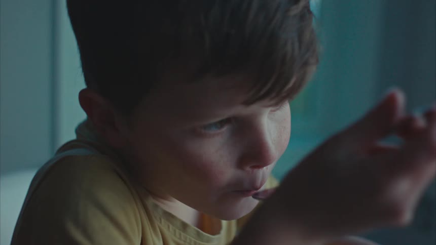 A young boy sits in a room eating