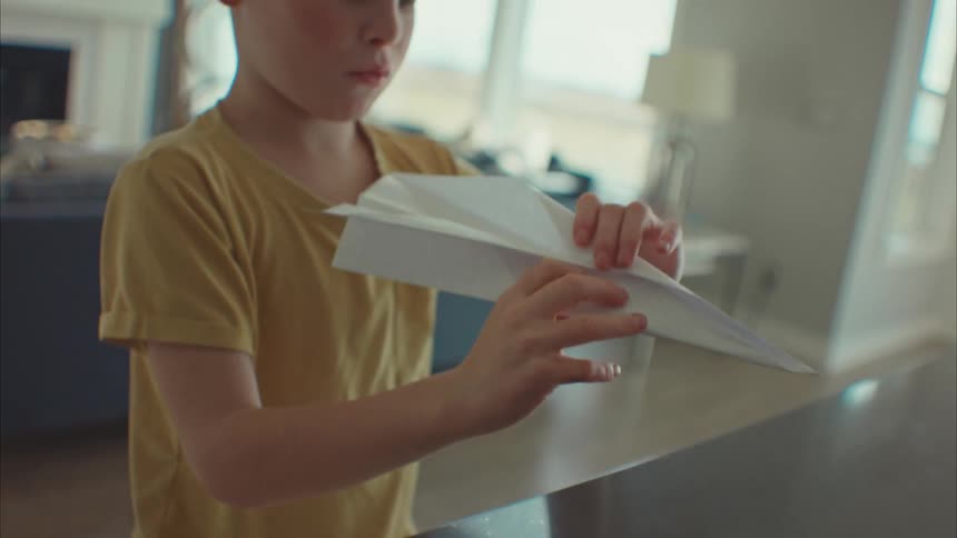 A clip of a boy making a paper plane