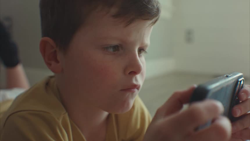 Portrait of a little boy concentrating on his iphone