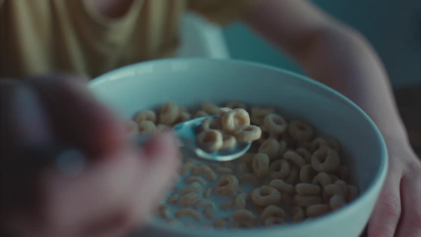 A little boy eating cereal mixing in milk with a spoon