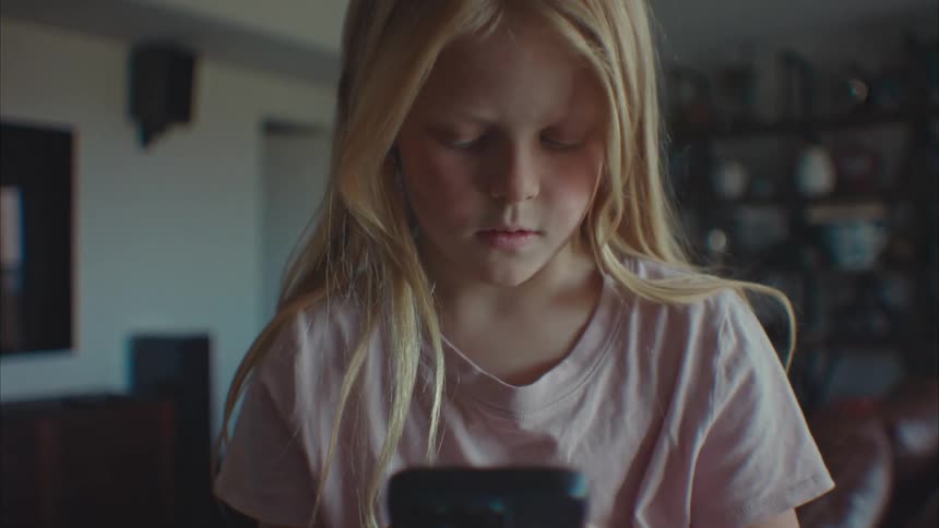 A female child using a smartphone while standing in the living room