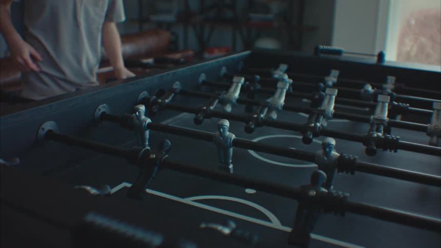 A boy child playing table soccer indoor during the day