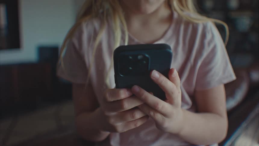 Closeup of a concentrated child using her cell phone